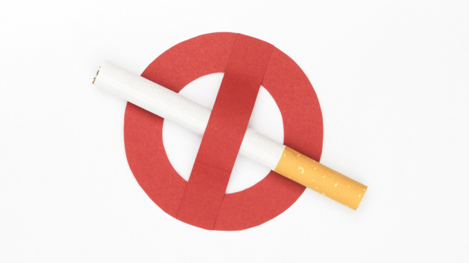 Fotografía de un cigarro y el símbolo de prohibición (círculo rojo con línea que diagonal sobre el cigarro)